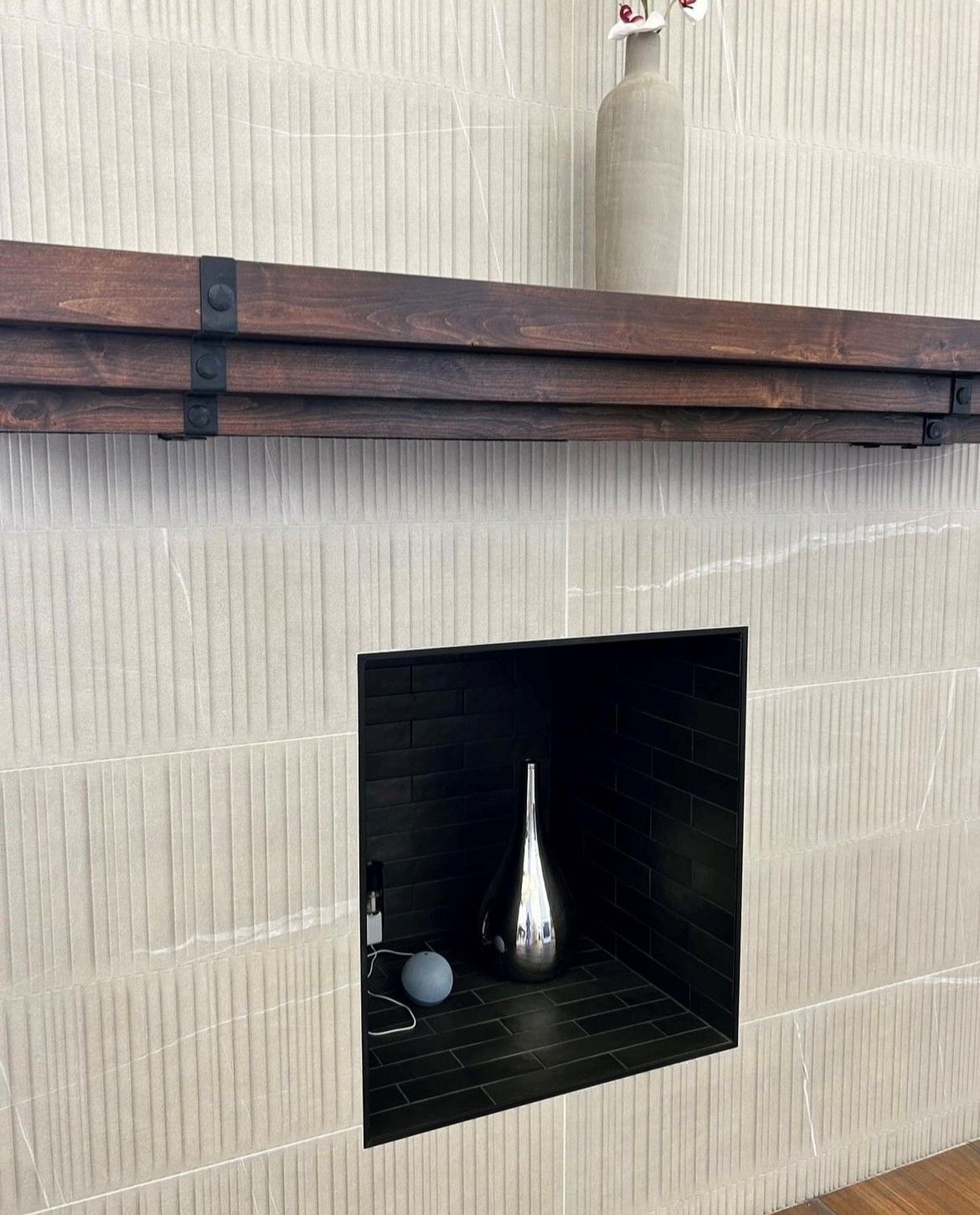 A fireplace with a wooden mantel and a vase on it