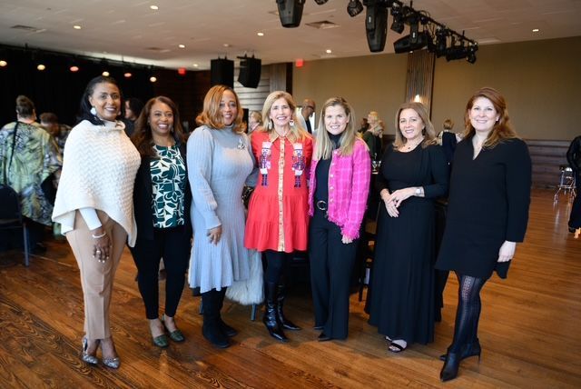 Group of women posing together indoors, with varied outfits and expressions.