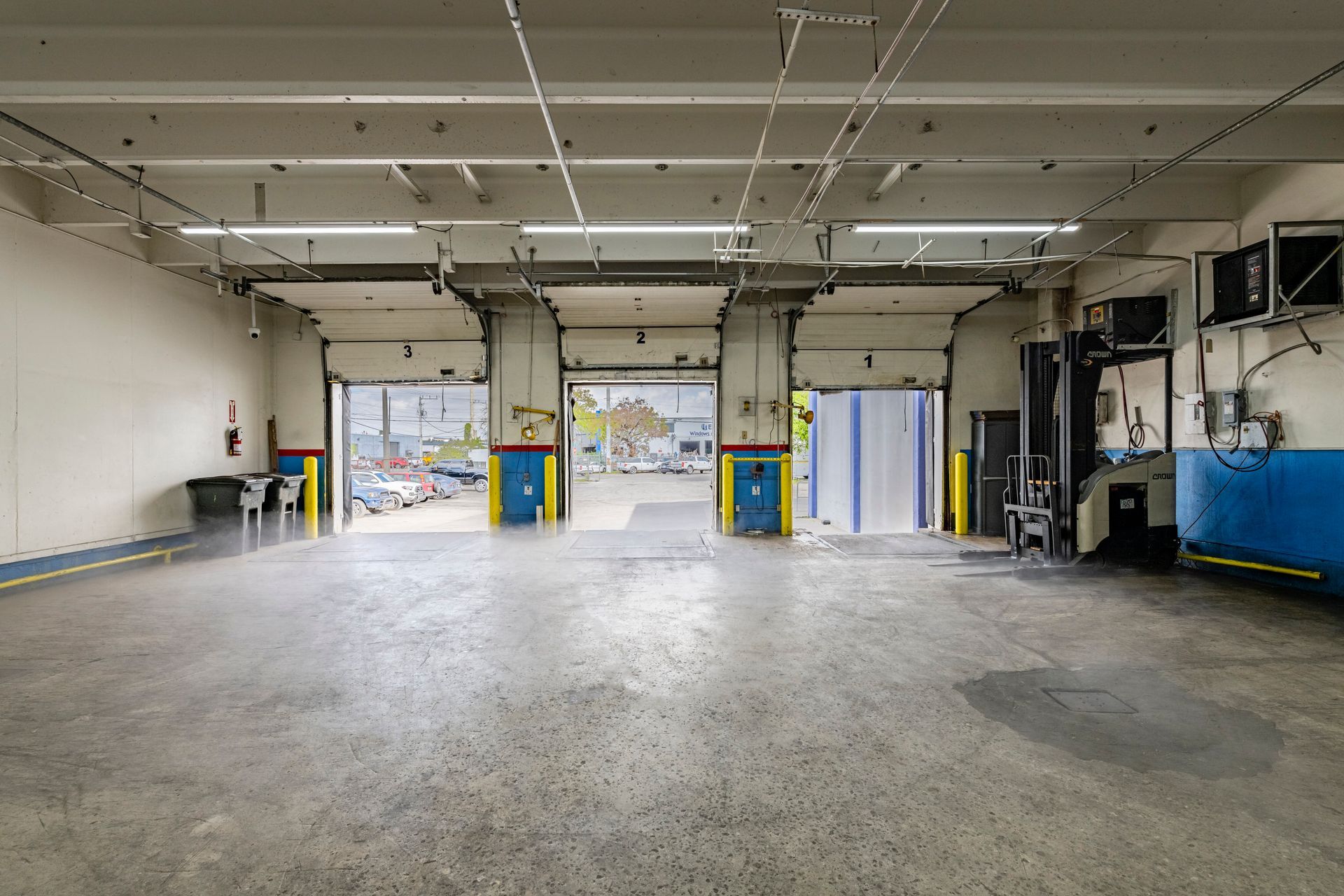 A large empty warehouse with a lot of doors open.
