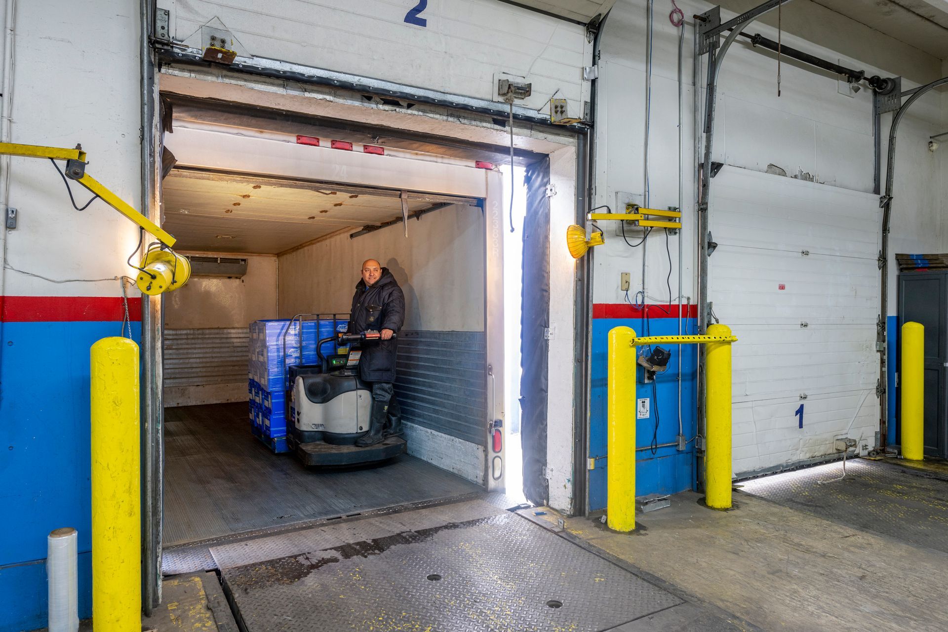 A man is driving a forklift through a warehouse door.