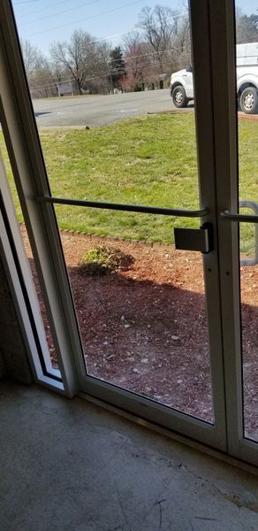 View through glass door of a green lawn and a driveway.
