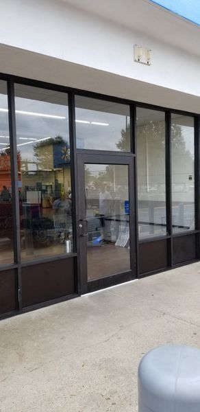 Exterior of a retail storefront with large windows and a glass door. The store appears closed.