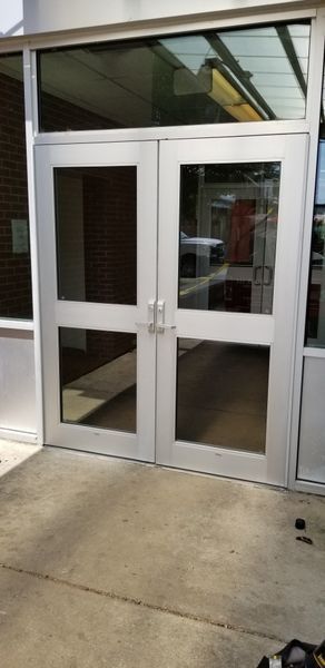 Double glass doors with silver frames and a concrete ground.