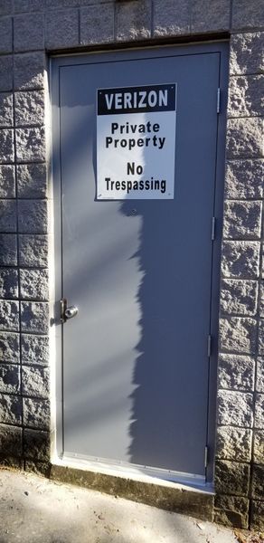 Verizon door on a gray block building. Sign reads 