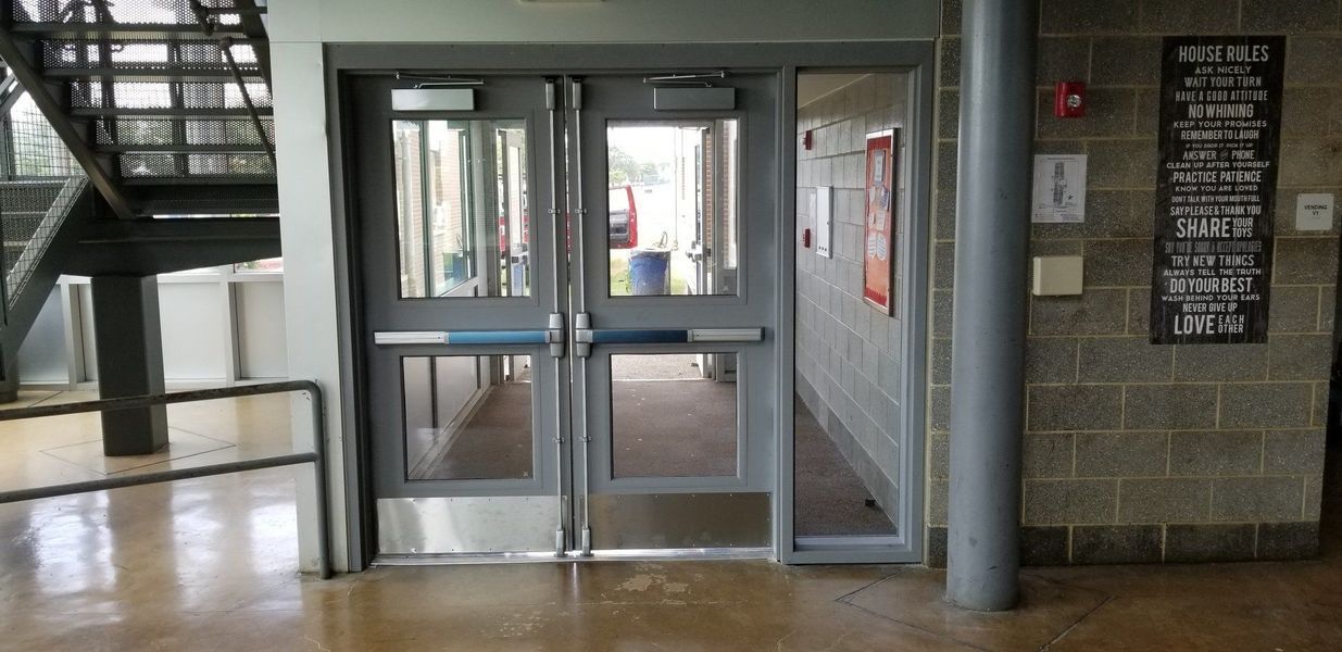 Double doors with glass panes, leading to an exterior view. A staircase is on the left. A brick wall is on the right.