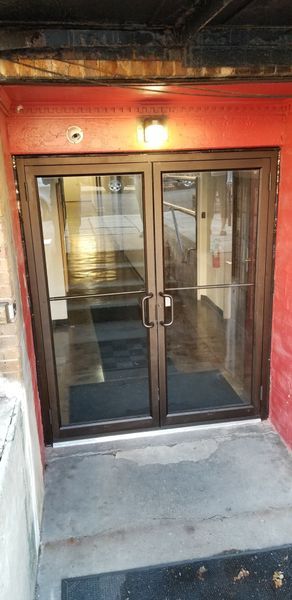 Double glass doors with brown frames; a red wall and a concrete step.