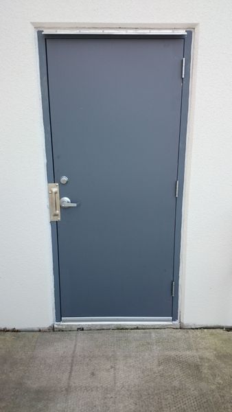 Gray door set in a white wall with a metal handle and frame.