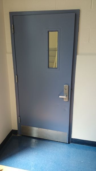 Blue door with small window and silver handle, set in a hallway.