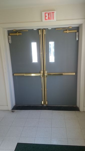 Double gray exit doors with gold bars and an illuminated 