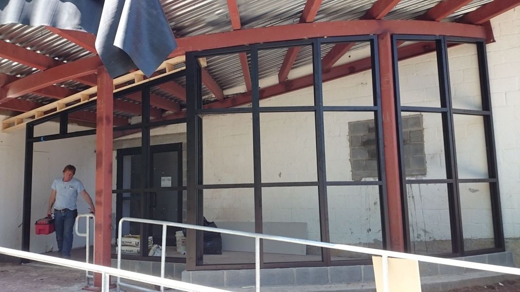 Exterior of a building with glass windows and a ramp. A person is walking near the entrance.