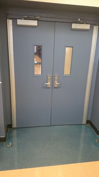 Blue double doors with small rectangular windows and silver hardware.