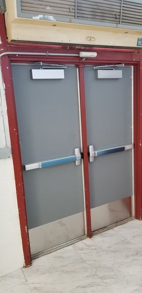 Double doors with a red frame, gray doors, and blue and silver push bars.