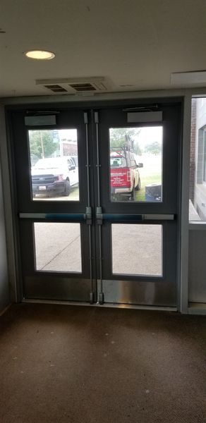 Double doors with glass panes and push bars lead outside. Cars are visible through the glass.