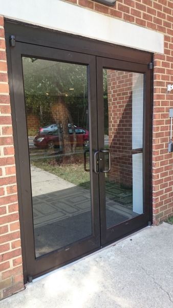 Glass double doors with dark frames set in a brick wall. Handles are visible.