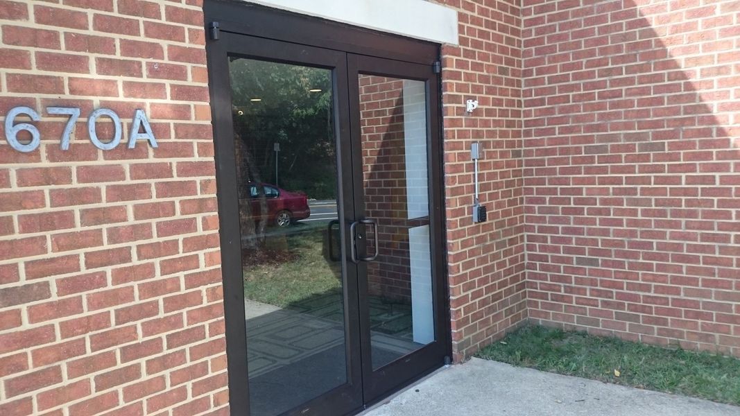 Exterior view of a building's entrance. The door is framed by brick walls. Address 