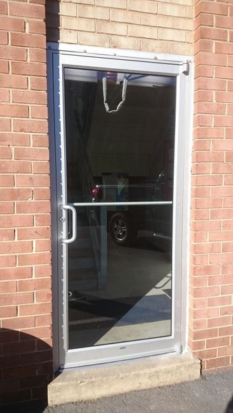 Glass door with a silver frame in a brick building.