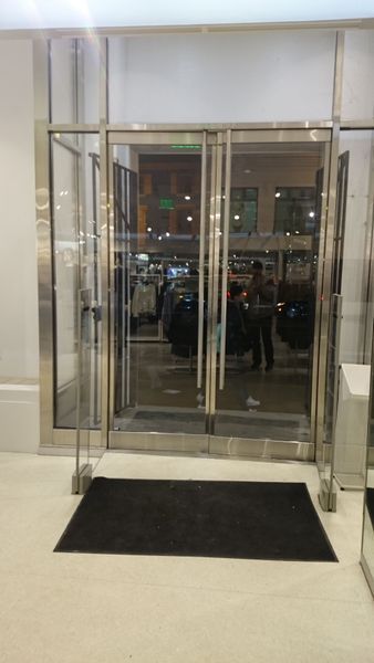 Glass doors of a store with a black doormat. Interior is visible through the doors.