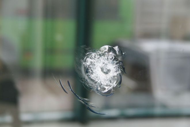 Shattered glass window with a circular impact point and radiating cracks.