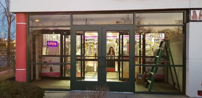 Storefront with glass doors; a ladder leans against the glass. Pink column on the left.