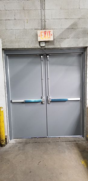 Gray double doors with blue push bars and an 