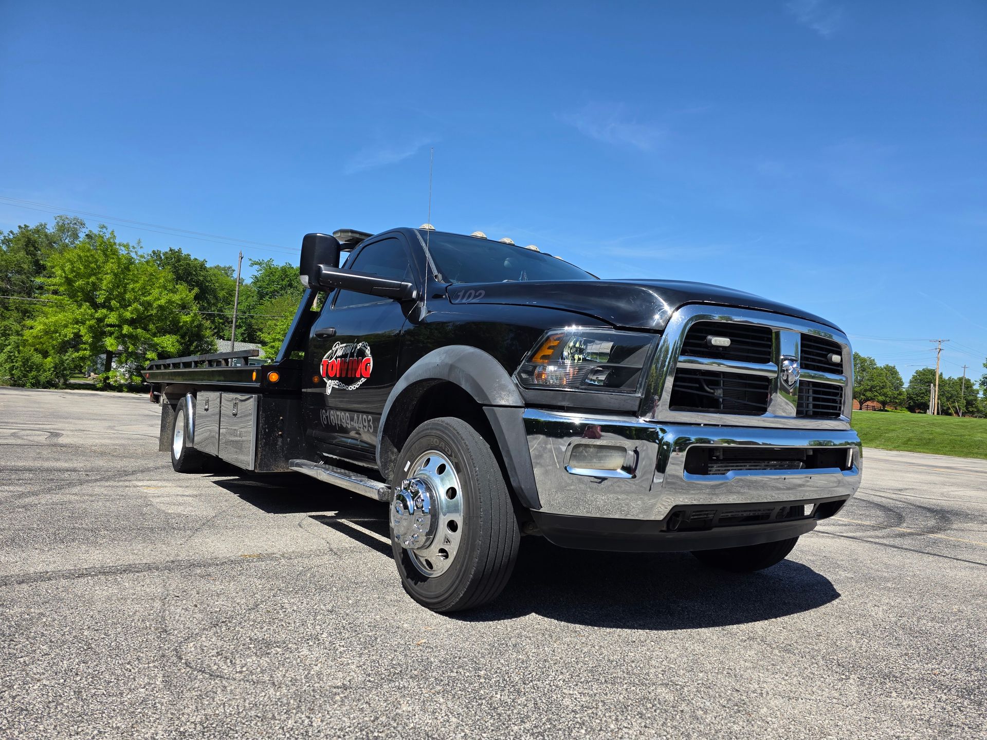 Black tow truck on asphalt, sunny day.
