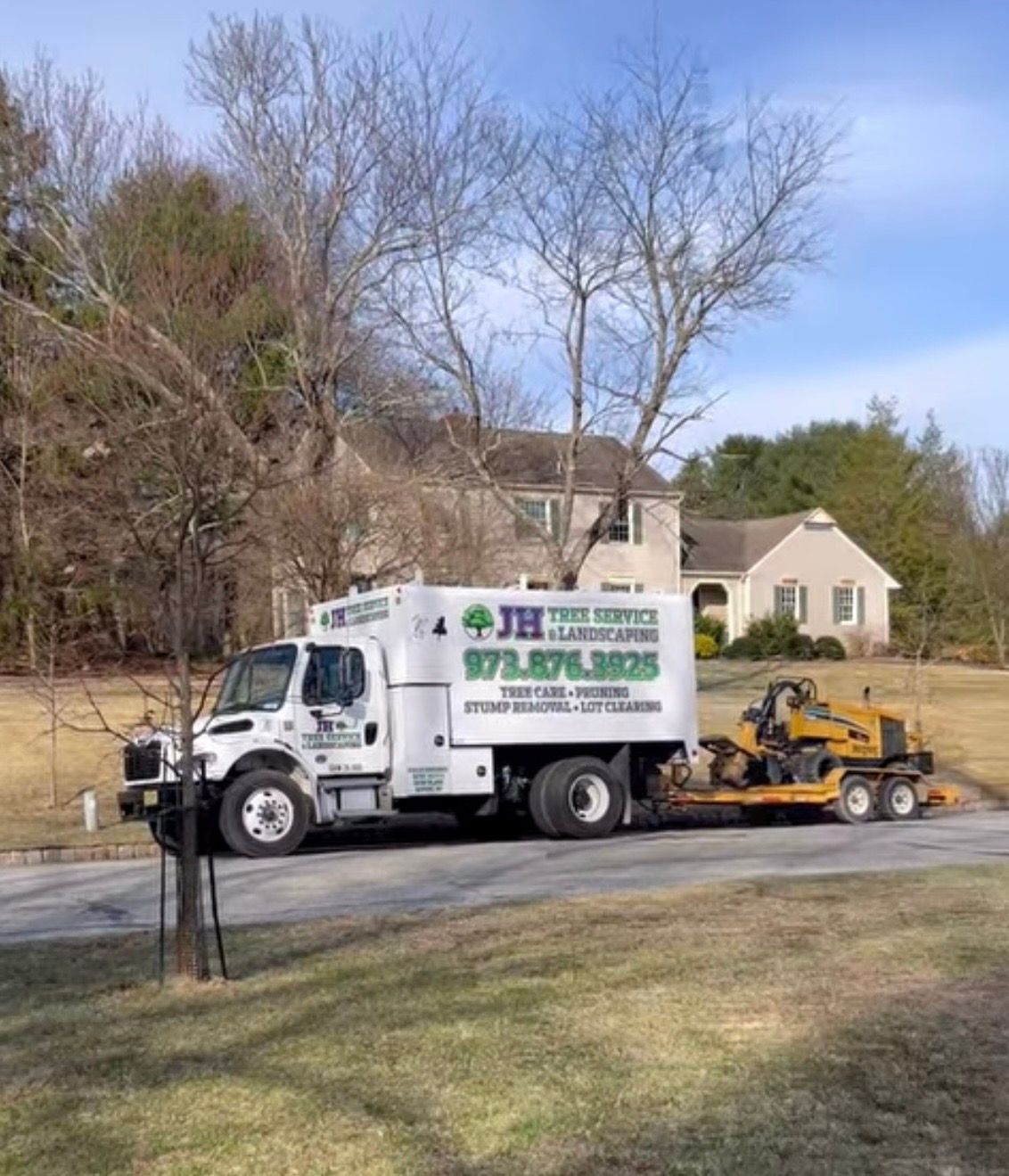 White JH Tree Service truck with trailer and equipment parked on a residential street. A house is in the background.