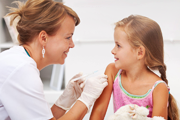 Child being vaccinated by a smiling nurse