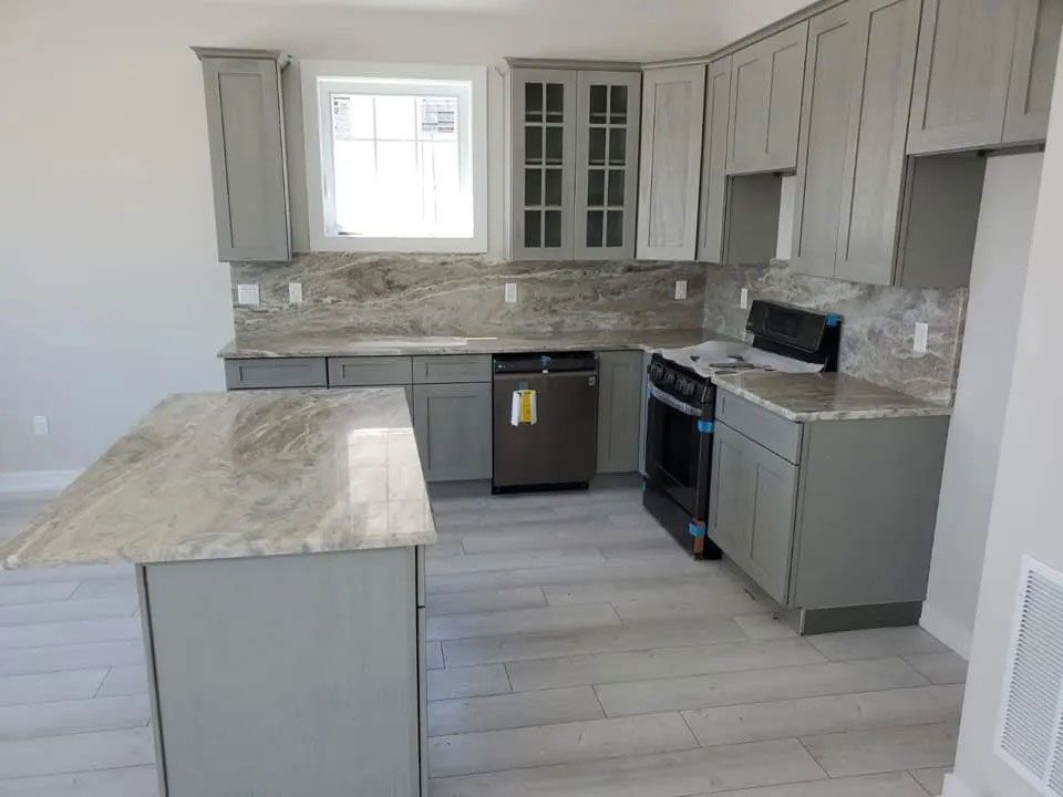 Modern gray kitchen with marble island, stainless appliances, and large window above the sink