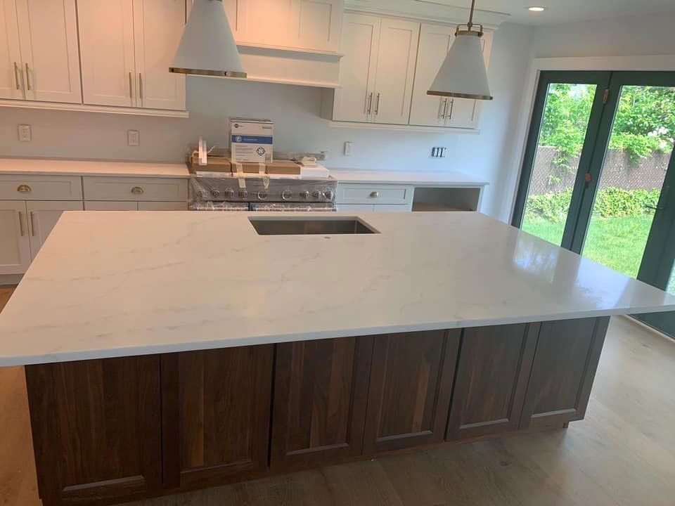 Modern kitchen with a large white island, dark wood cabinets, and sliding glass doors to a green yard