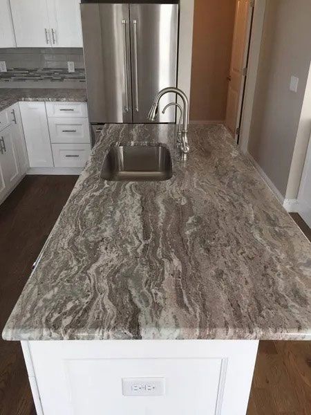 Kitchen island with gray stone countertop and built-in sink, viewed from the end of the counter
