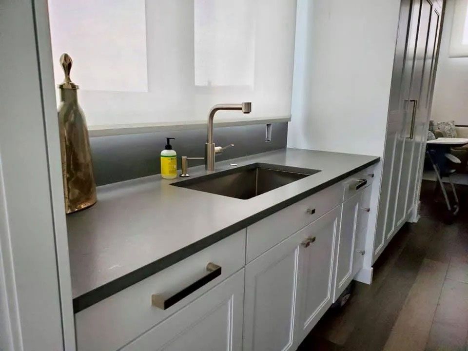 Modern kitchen countertop with stainless sink, gray cabinets, and dark wood flooring