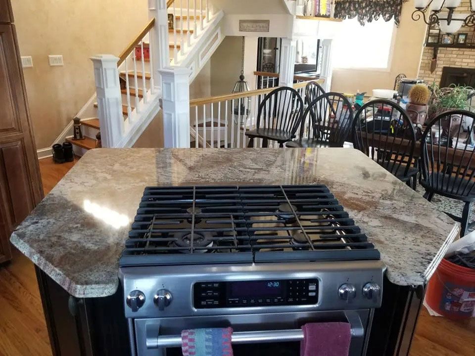 Kitchen island with granite countertop and built-in gas cooktop in a bright open dining area