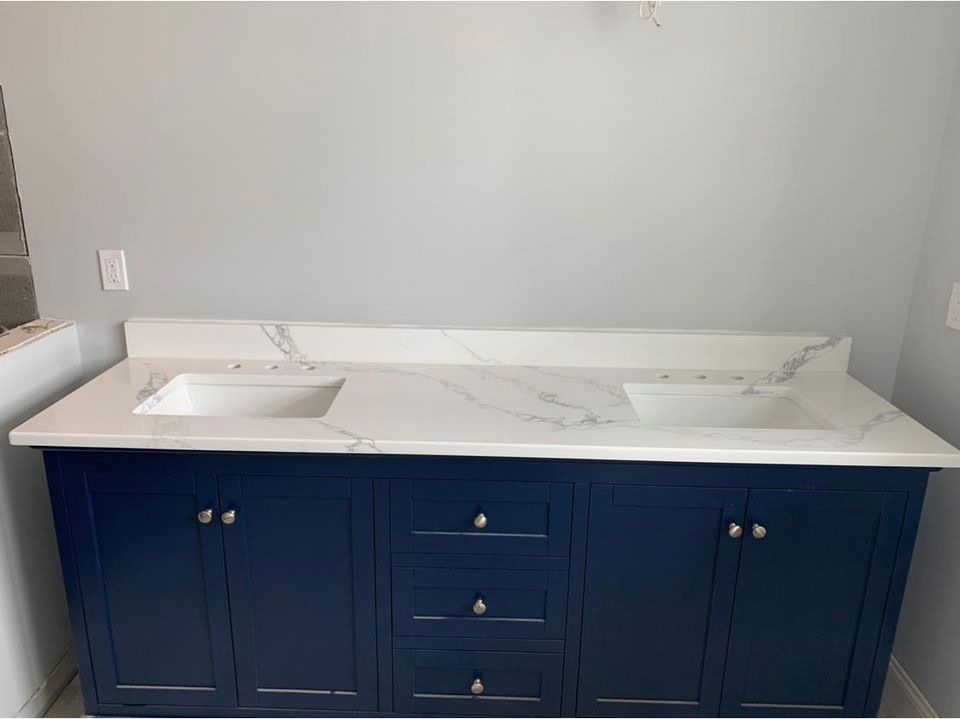 Blue bathroom vanity with white countertop and double sinks against a light gray wall