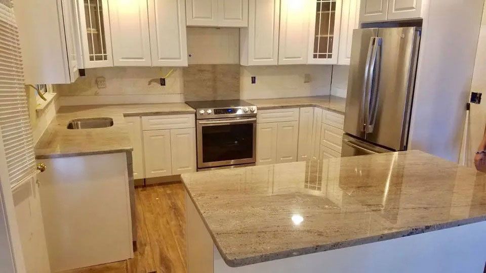 Bright modern kitchen with white cabinets, stainless steel appliances, and a granite island countertop.