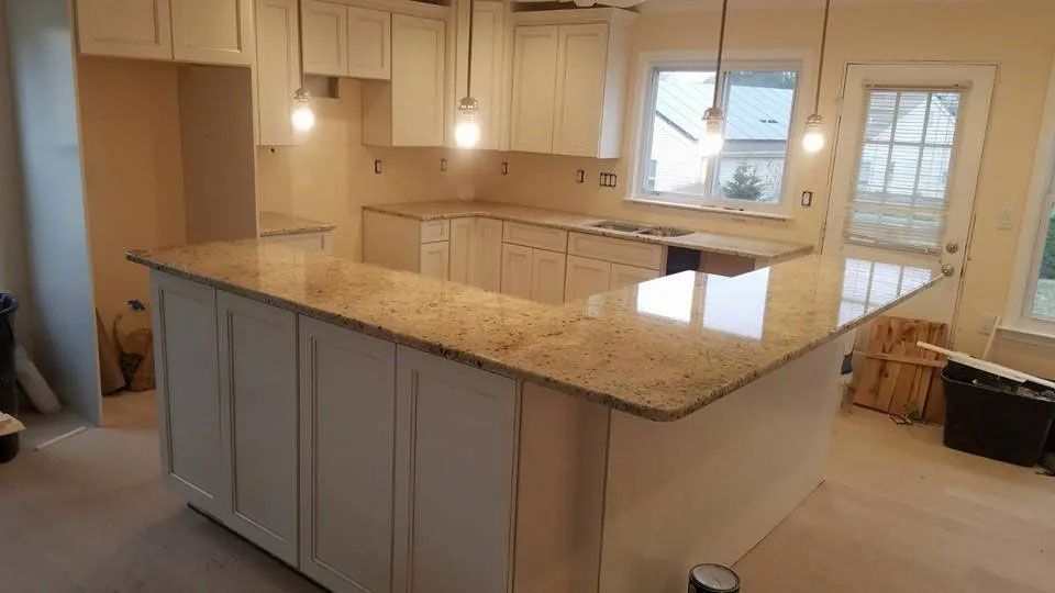 Bright kitchen with a large granite island, white cabinets, pendant lights, and a windowed door.