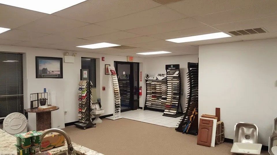 Empty carpeted room with shelves, framed pictures, and a small table in a basement-like office space