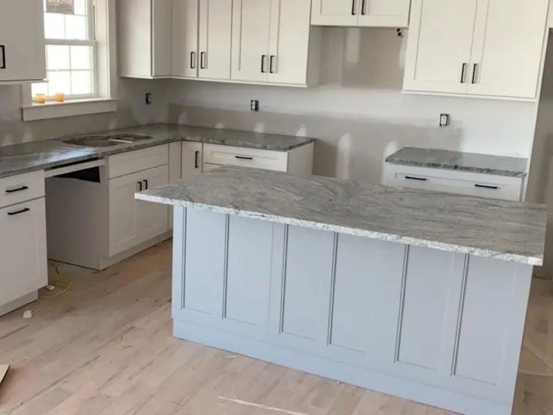 Bright modern kitchen with white cabinets, gray island, stainless appliances, and light wood flooring