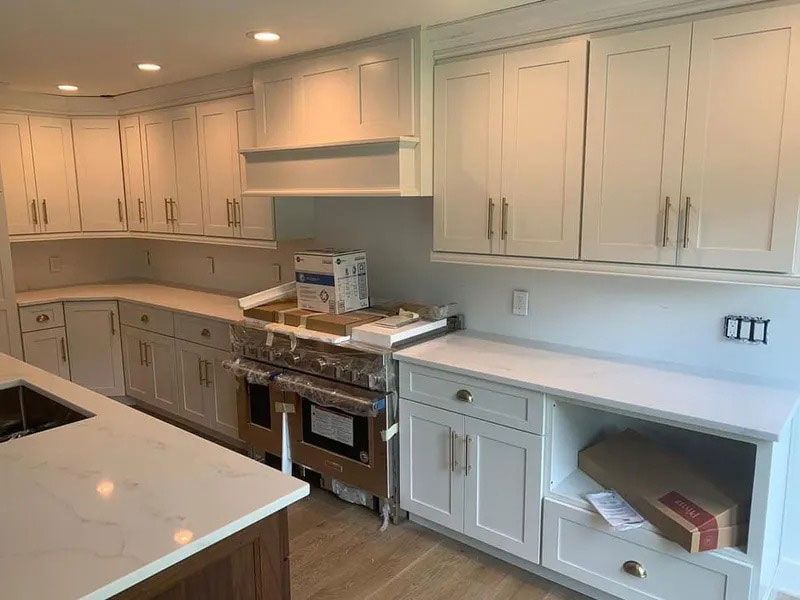 Modern white kitchen with marble island, cabinets, stainless stove, and open shelves
