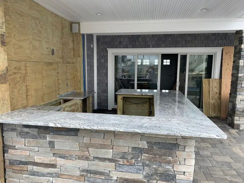 Empty stone reception counter at an unfinished building entrance with glass sliding doors.