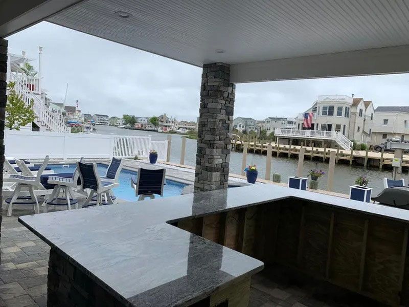 Outdoor patio with blue lounge chairs and a waterfront view under a covered roof