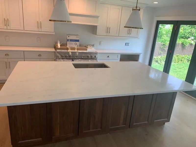 Modern kitchen with large white island, dark wood cabinets, and sliding glass door to a green yard