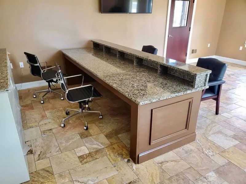 Conference room with long granite table, rolling chairs, and beige tiled floor.