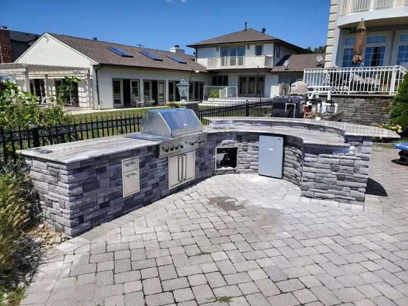 Outdoor stone memorial wall with plaques and a curved paved courtyard in a residential neighborhood