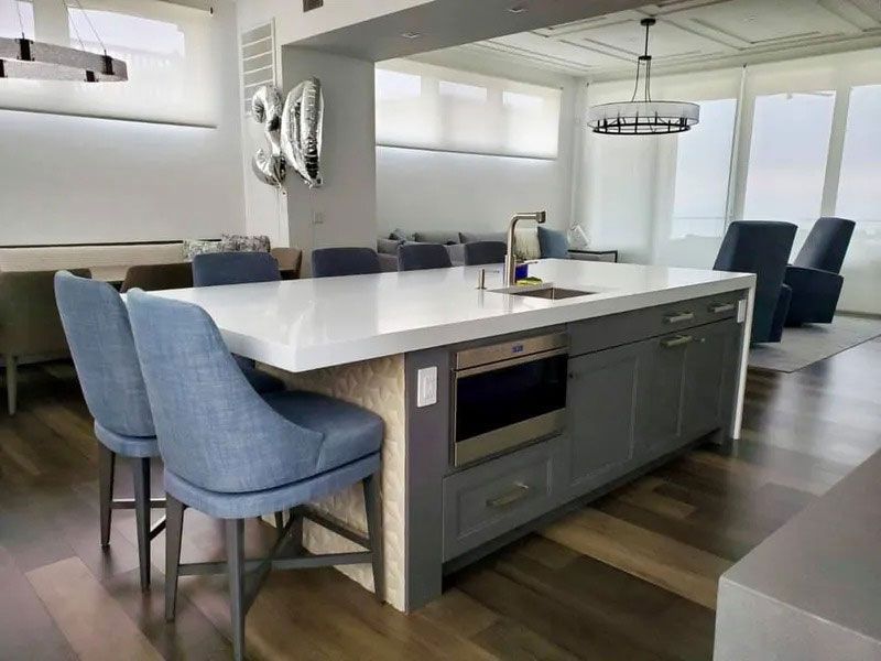 Modern kitchen with a large island, white countertop, blue chairs, and adjacent dining area