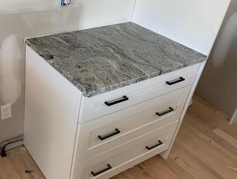 White dresser with gray granite top in a corner