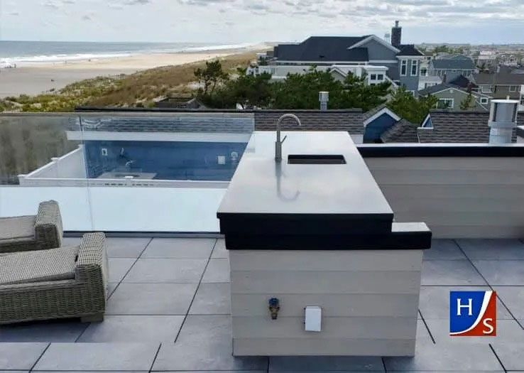 Rooftop patio with pool and hot tub overlooking the ocean and coastal homes.