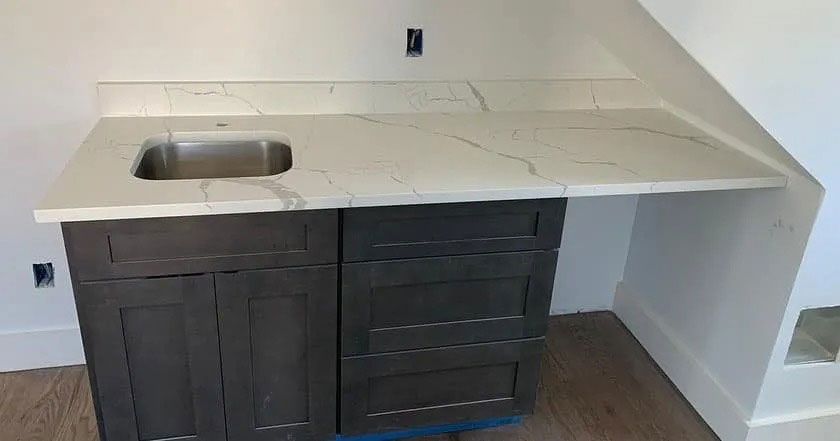 Kitchen countertop with built-in sink and dark cabinets against a white wall