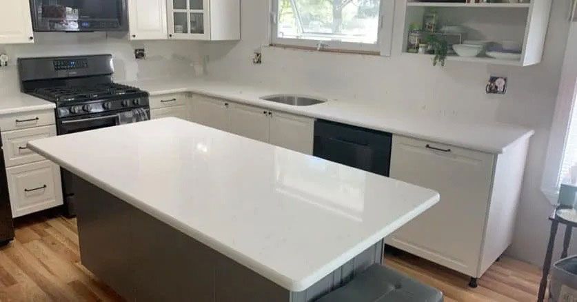 Bright white kitchen with island, stove, sink, and black dishwasher by a window