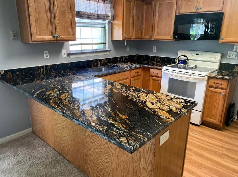 Kitchen with black-and-gold granite island, wood cabinets, white stove, and stainless sink