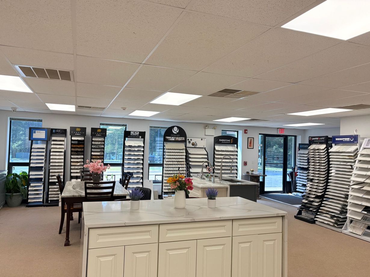 Bright office with sample racks, tables, and a central island under fluorescent lights